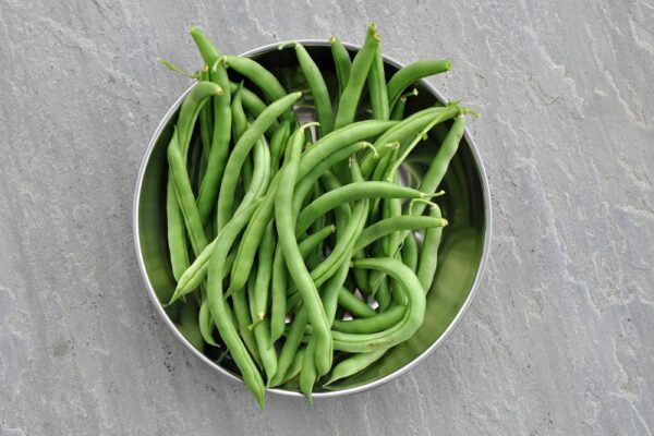 Fresh green beans in a stainless steel bowl.