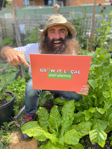 Man holding Grow It Local Seed Service sign.