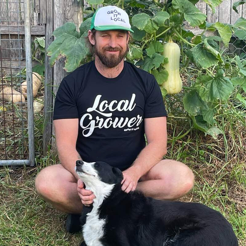 Man in garden with dog and squash plant.