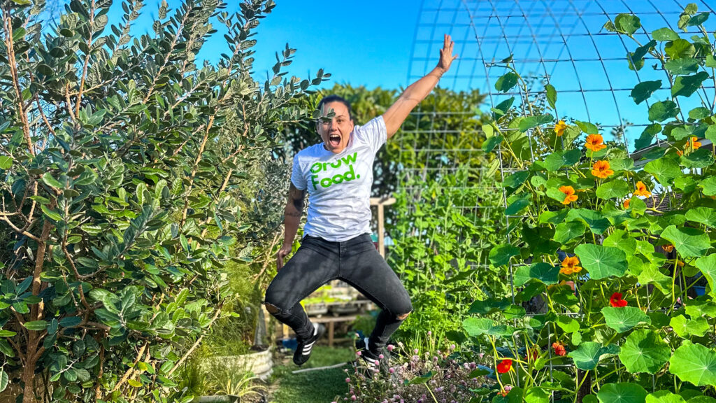 Person jumping joyfully in a lush garden.