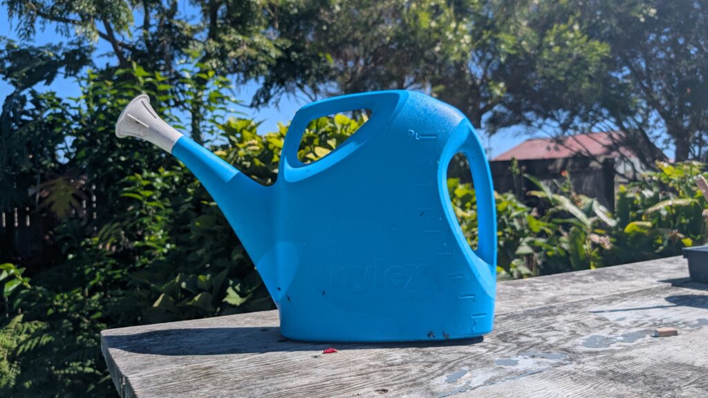 Blue watering can on outdoor table