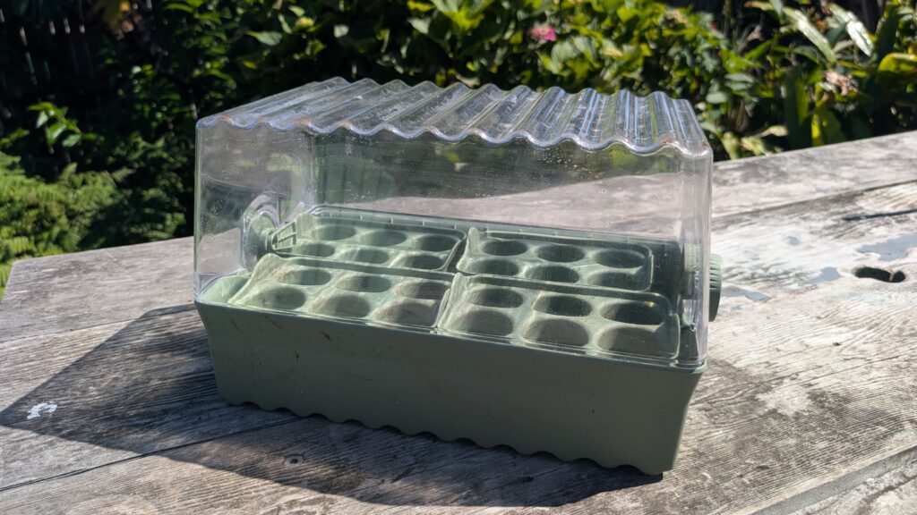 Plastic seed starter greenhouse on wooden table.