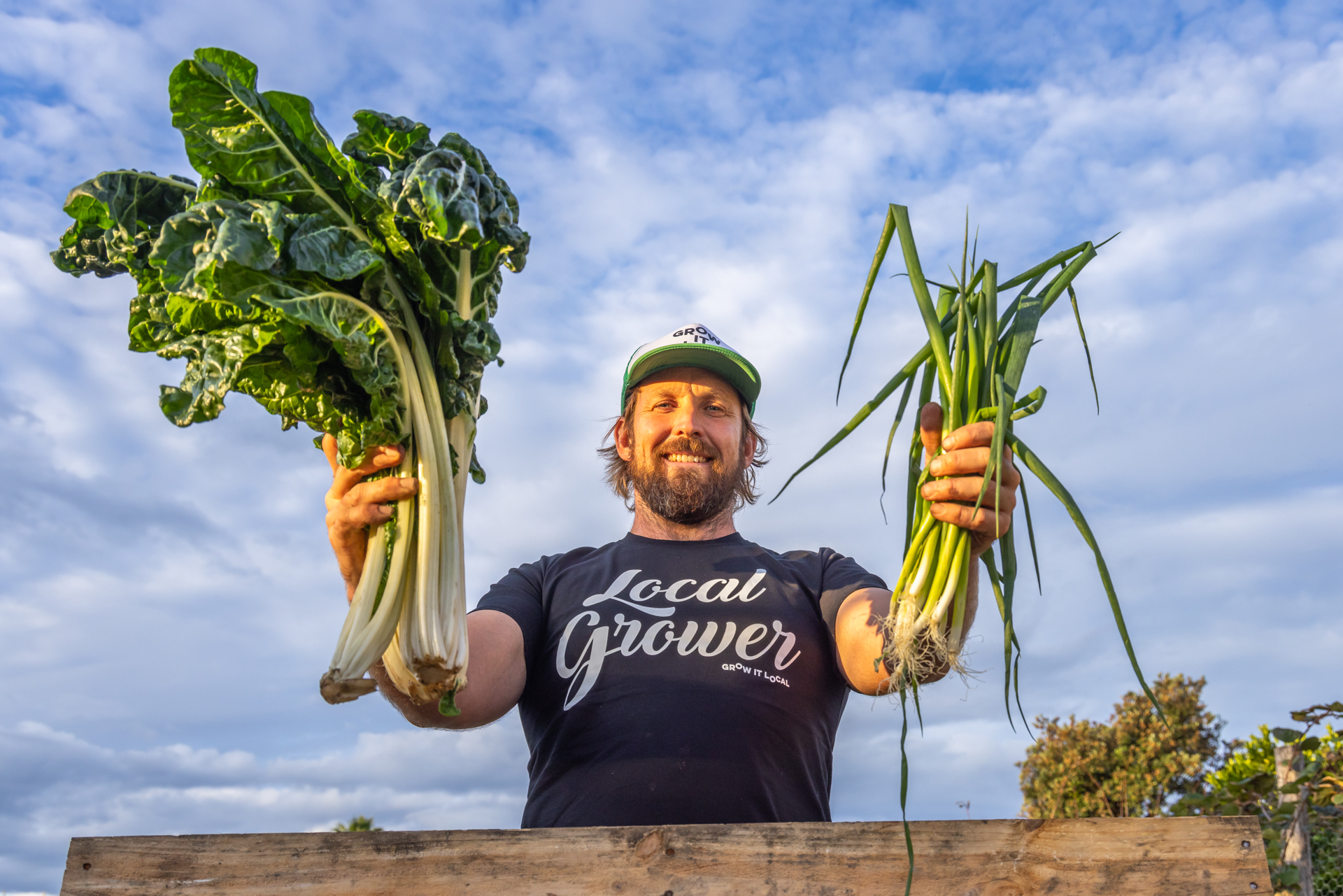 Local farmer holding fresh vegetables, sky background.