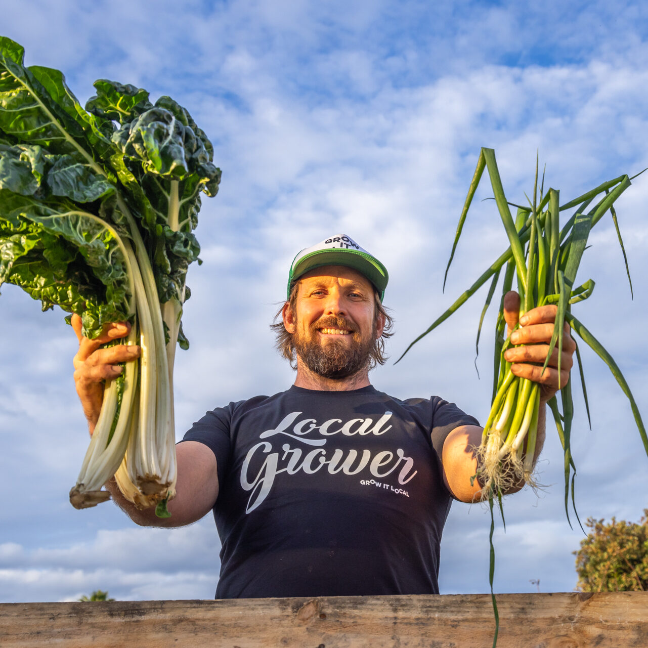 Farmer holding fresh vegetables outdoors.