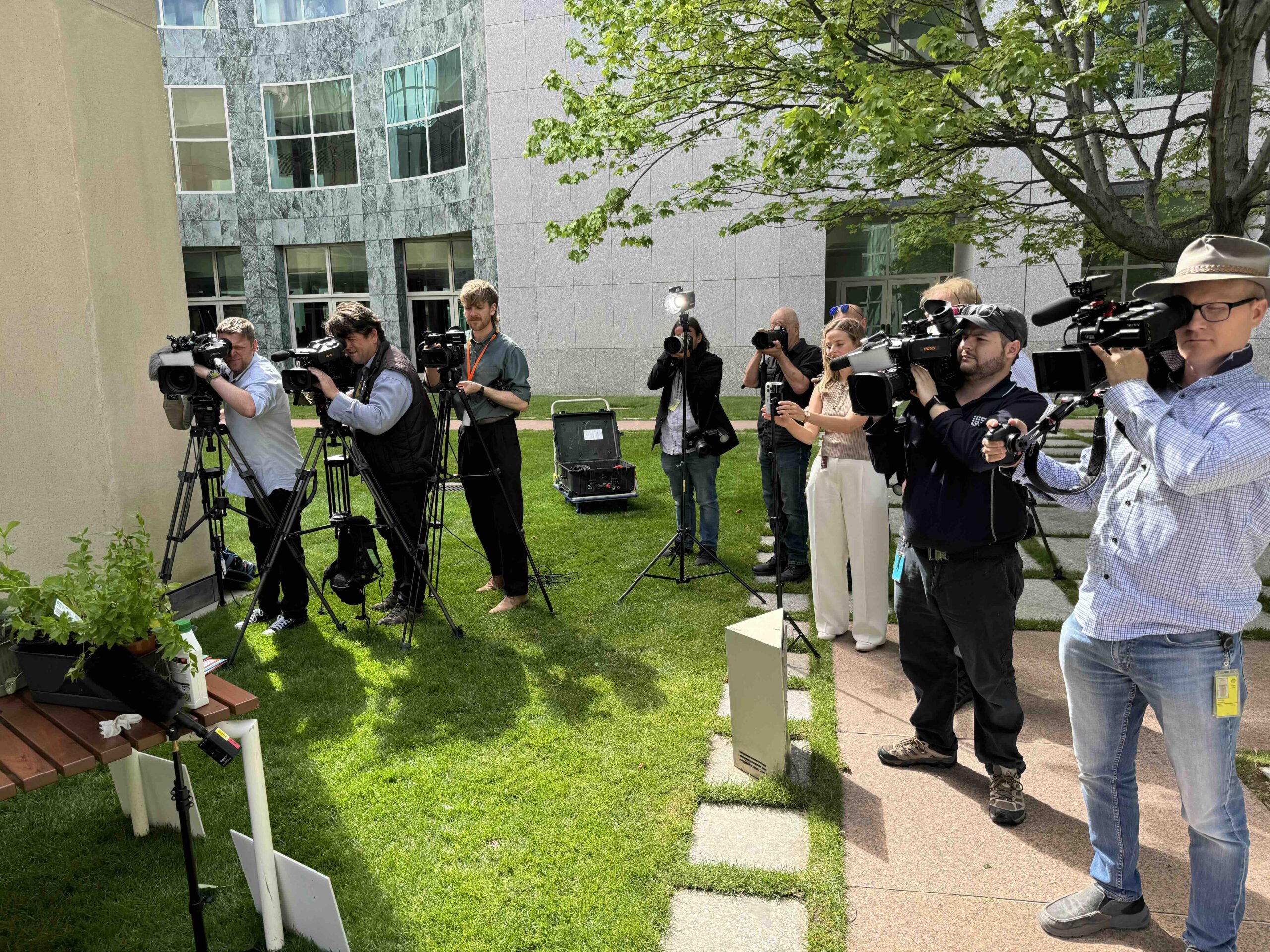 Journalists photographing outdoor event at Parliament House, Canberra.