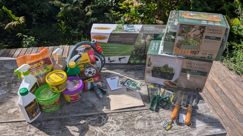 Garden tools and supplies on wooden table outdoors.