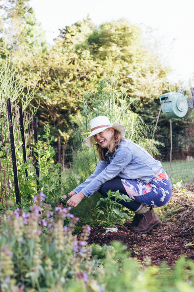 Woman gardening happily in lush green setting.