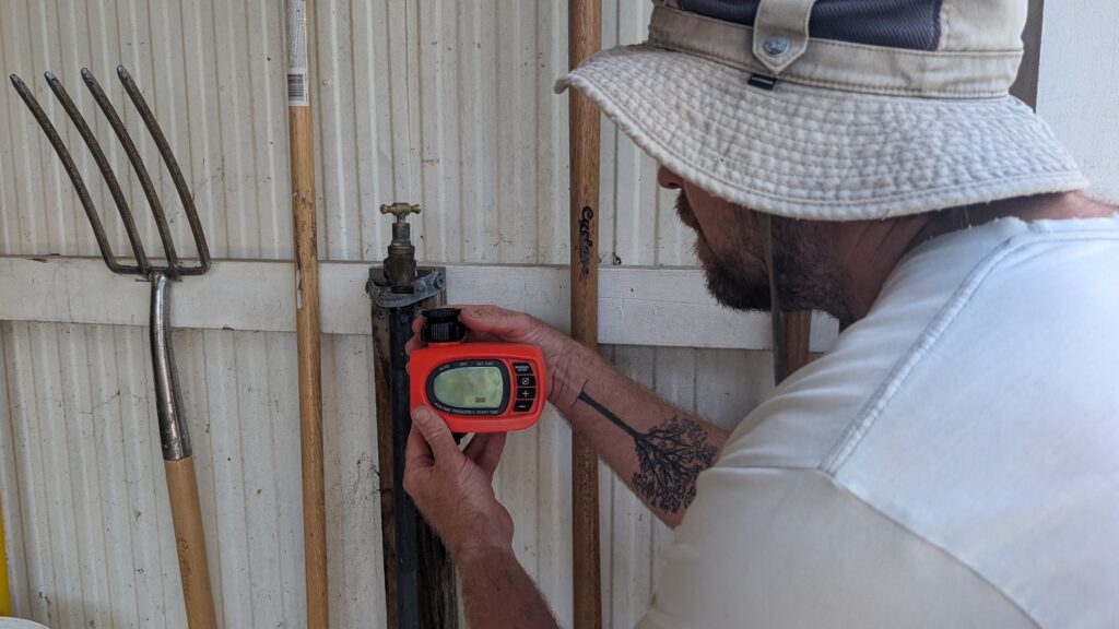 Man adjusting garden tap with water timer.