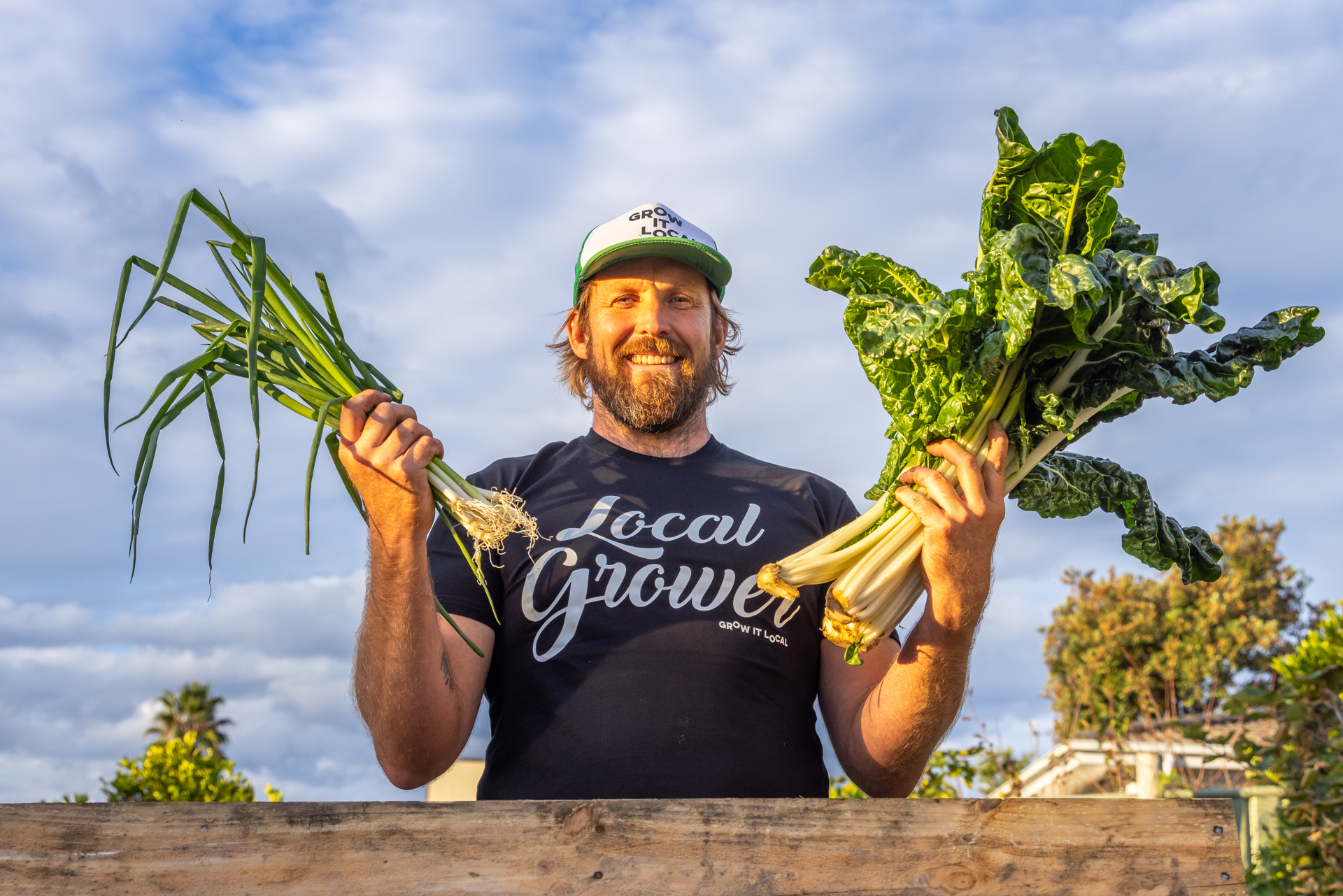 Farmer holding fresh onions and chard, outdoors