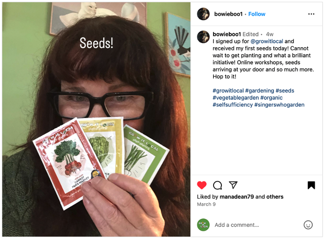 Woman holding seed packets indoors.