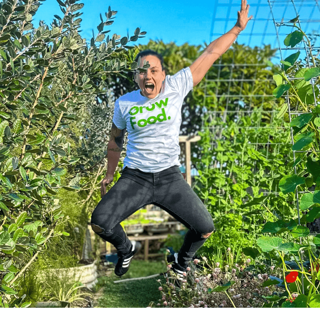 Person jumps enthusiastically in a lush garden.