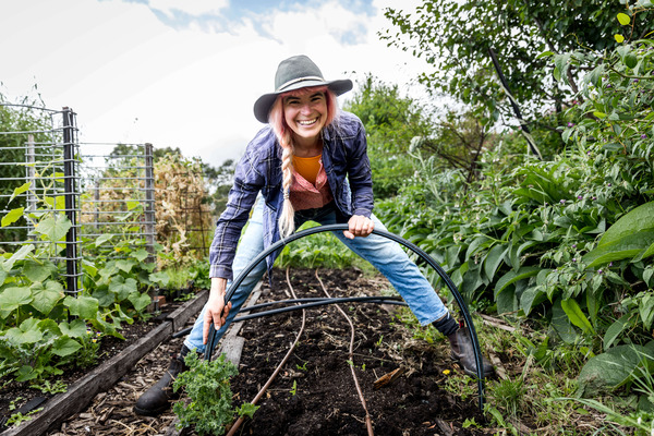 Woman gardening with hoop frame in vegetable patch.