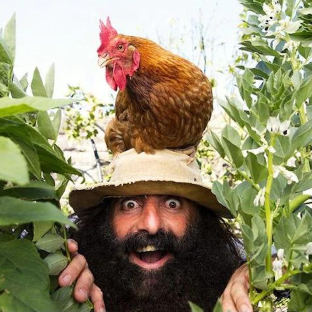 Man with chicken on hat in garden