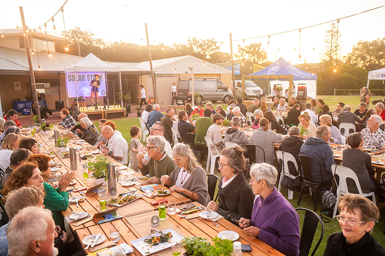 Community outdoor dinner event at sunset