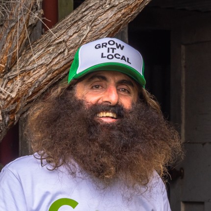Smiling man with beard wearing 'Grow It Local' cap.