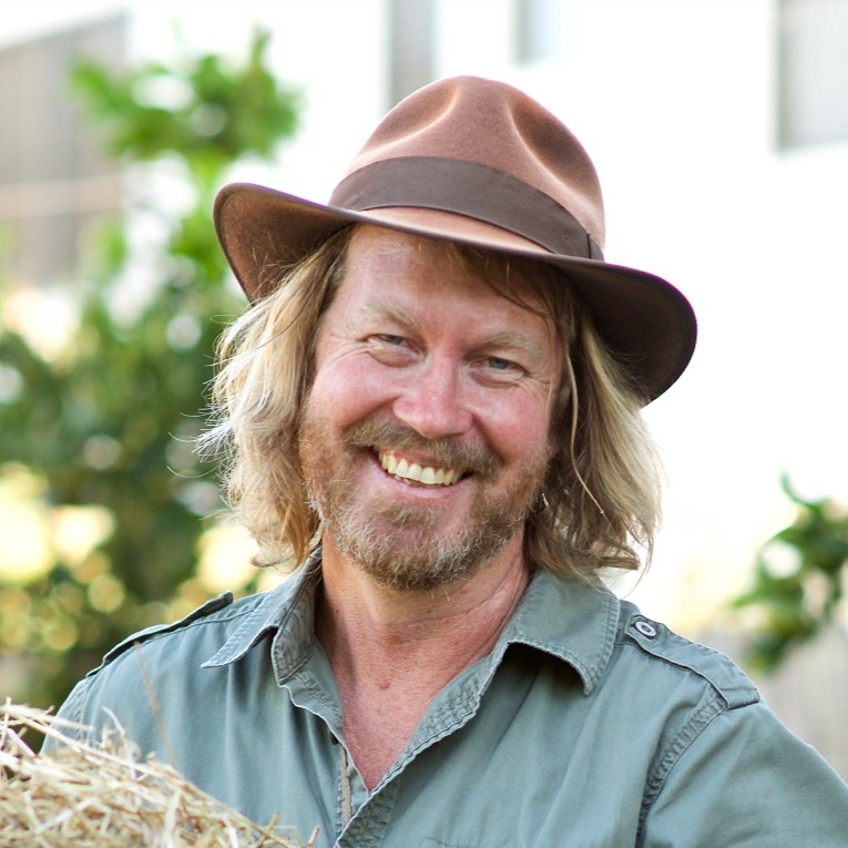 Man smiling outdoors, wearing a hat.