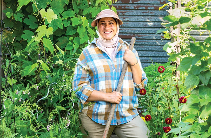 Smiling gardener with spade in vibrant garden.