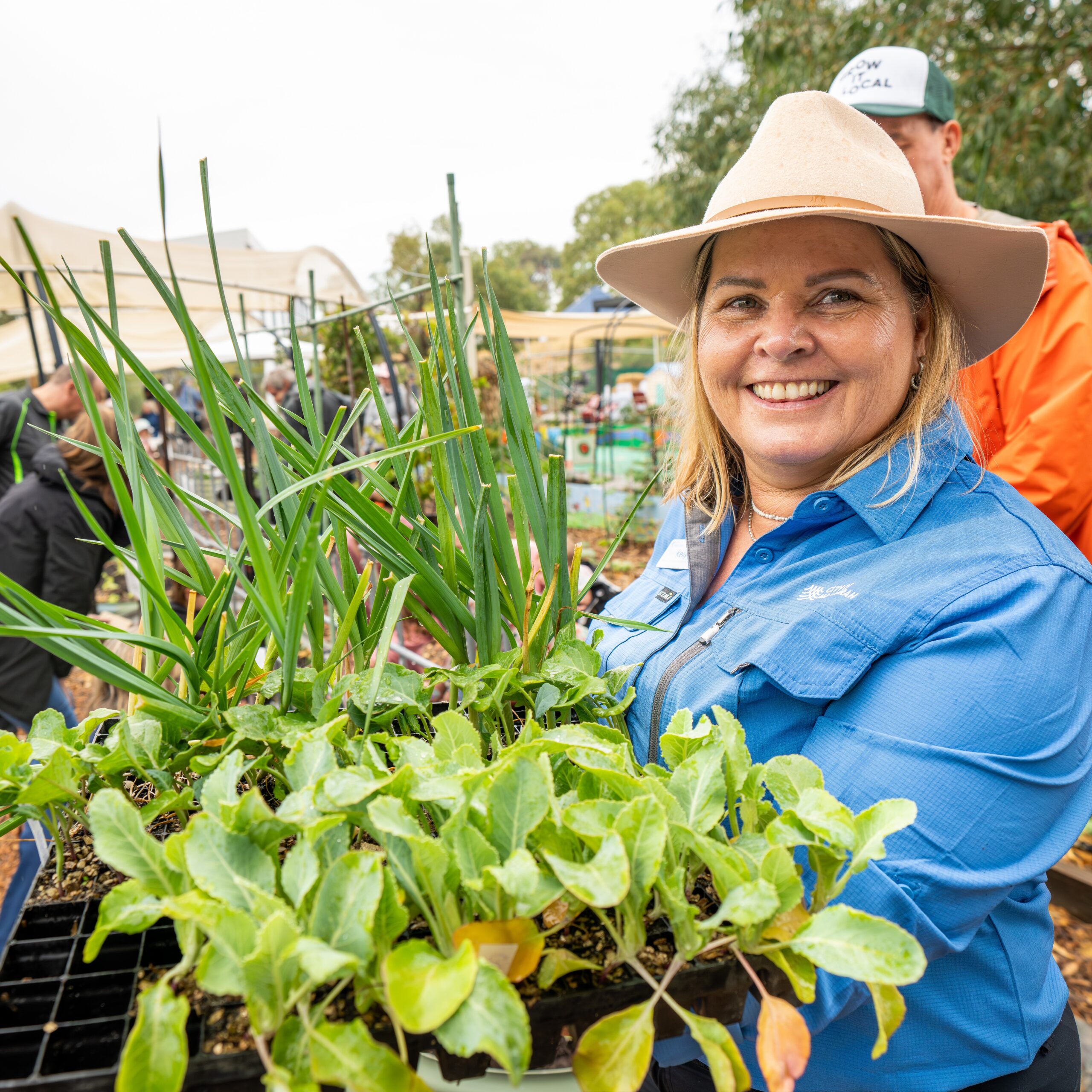 Smiling woman holding plants at a market